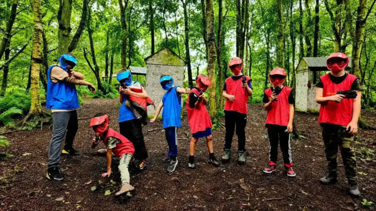 Children in red and blue bibs playing in the woods
