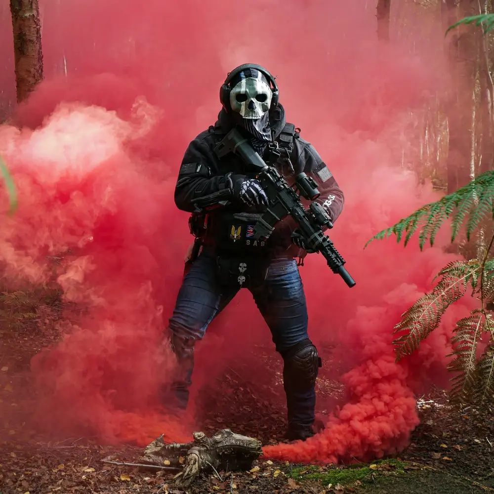 An airsoft player in a skull mask walking through red smoke